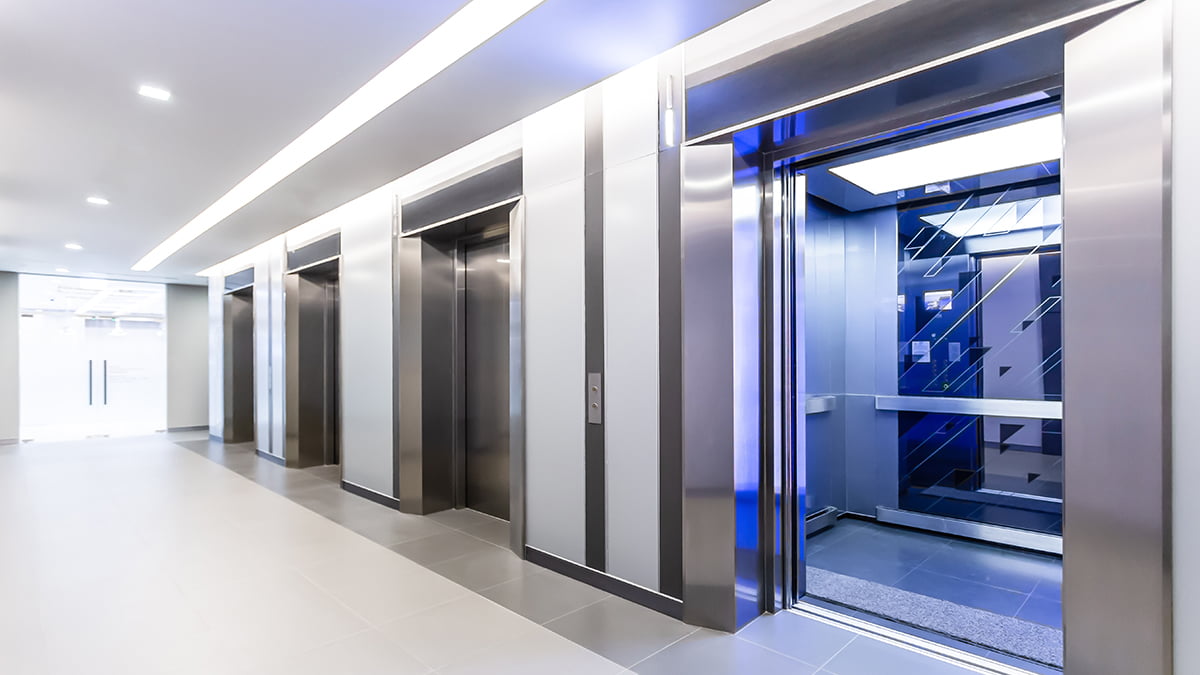 Hall moderno com elevadores em aço inox e cabine aberta